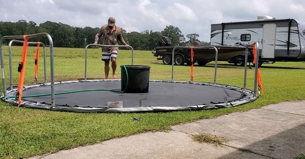 Why is it necessary to trim the grass underneath a trampoline?